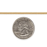 Gold-filled cuban chain next to a quarter dollar coin on a white background